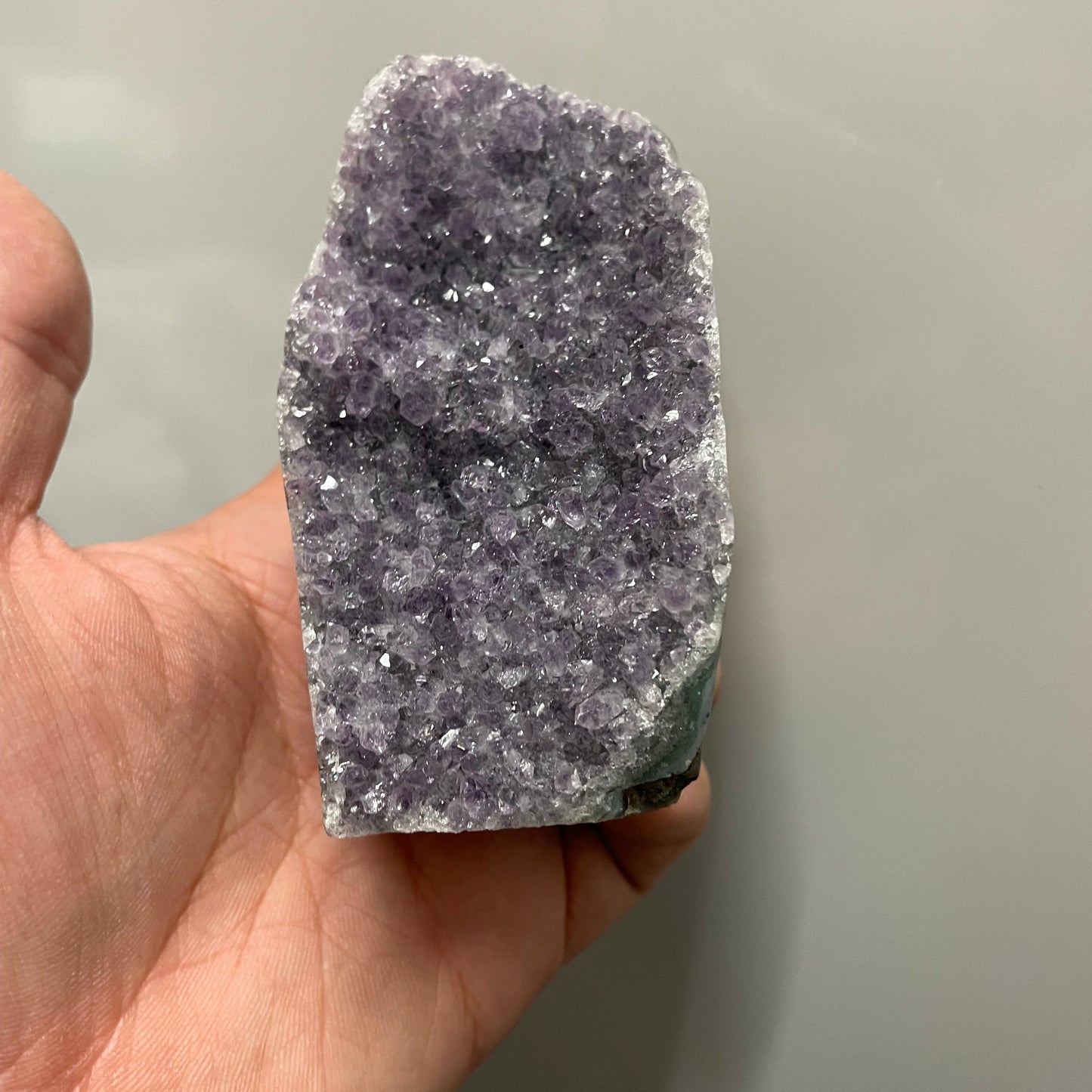 Hand holding a crystal rock against a neutral background